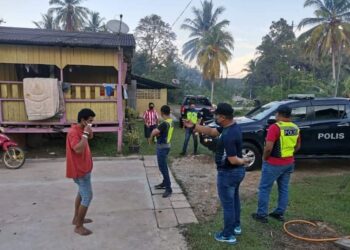 Anggota polis memeriksa seorang lelaki dalam operasi pematuhan prosedur operasi standard di Felda Bukit Aping Timur, Kota Tinggi, Johor.