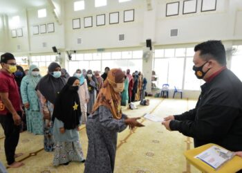 TUANKU Syed Faizuddin Putra Jamalullail (kanan) berkenan menyerahkan sumbangan kepada salah seorang asnaf yang layak menerima agihan bantuan daripada MAIPs di Simpang Empat, Arau, Perlis hari ini.- UTUSAN