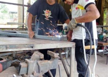 SHAHRUL Nizam Badrulsham (kanan) dibantu Badrulsham Baharom melakukan kerja-kerja di bengkel besinya di Kampung Teluk Temelah, Mukim Siong, Baling, Kedah. - UTUSAN/NORLIA RAMLI