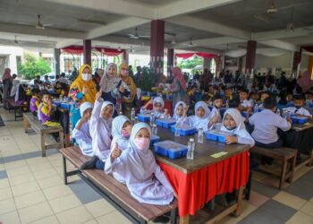 MURID SK Haji Salleh Masri menikmati makanan percuma yang disumbangkan Bernas dan CSR dalam Promak di Kuala Kedah, Alor Setar. - UTUSAN/SHAHIR NOORDIN