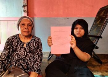 ZALEHA IBRAHIM bersama-sama anak angkatnya, Siti Hanisah menunjukkan salinan surat beranak di rumahnya di Lorong Yunos, Kampun Dalam, Pontian.