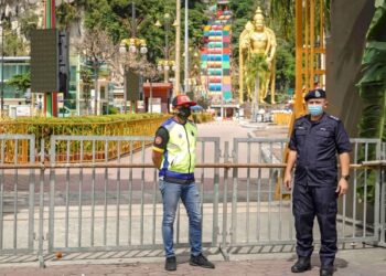 ANGGOTA polis mengawal pekarangan Kuil Sri Subramaniar Swamy, Batu Caves, Selangor dengan latar belakang patung Dewa Murugan pada Januari lalu. – UTUSAN/FARIZ RUSADIO