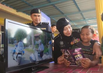 SURINA Saad menerangkan mengenai keselamatan jalan raya kepada salah seorang murid pada majlis pelancaran Op Selamat 19 Tahun Baharu Cina dan Karnival Usahawan Seri Tunjong 2023 di Sekolah Kebangsaan (SK) Seri Tunjong, Padang Besar, Perlis hari ini.- UTUSAN/SYED AZLAN SAYID HIZAR