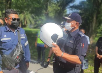 BAHARUDIN Mat Taib memakaikan topi keledar baharu kepada seorang penunggang motosikal selepas merasmikan Op Selamat itu di Plaza Tol Kemuning Lebuhraya KESAS di Shah Alam, Selangor, hari ini.