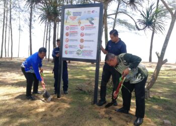 DR. Azman Ibrahim (kanan) memasang papan tanda amalan baik di kawasan pendaratan penyu di Pantai Teluk Mak Nik, Kemaman, hari ini. 