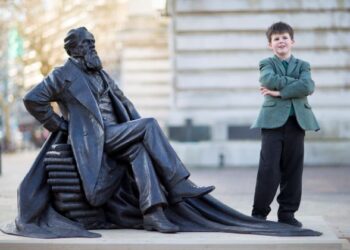 OLIVER DICKENS, 9, bergambar bersama replika tugu nenek moyangnya, Charles Dickens di Guildhall Square, Portsmouth.-AFP