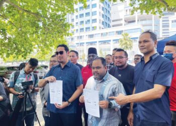 AHMAD Ikhwan Fadhli (tengah) dan Wan Ahmad Fayhsal Wan Ahmad Kamal (berkaca mata hitam) menunjukkan laporan polis yang dibuat di hadapan Ibu pejabat Polis Daerah Dang Wangi, Kuala Lumpur, semalam.