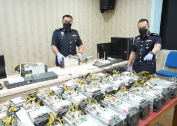 AHMAD Ridhwan Mohd Nor @ Saleh (kanan) menunjukkan antara peralatan digunakan bagi melombong Bitcoin yang dirampas polis dalam dua serbuan bersama TNB Seal di Kuala Langat, Selangor.