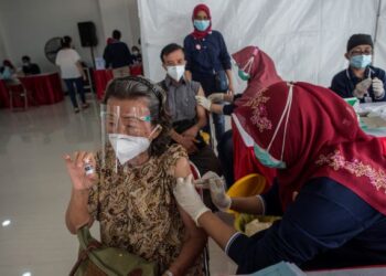 SEORANG warga emas menerima suntikan vaksin Covid-19 di Surabaya, Indonesia. - AFP