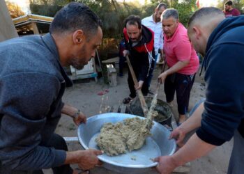 ORANG ramai menyediakan roti Bazin di Tajoura, timur Tripoli, Libya kelmarin. - AFP