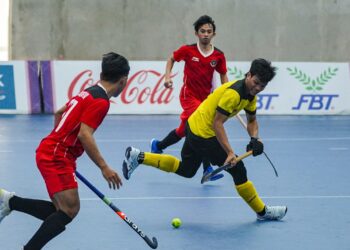 PEMAIN negara, Syed Mohamad Syafiq Syed Cholan mengawal bola dalam aksi final hoki dalam dewan menentang Indonesia di Dinosaur Park Hall.