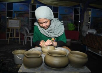 NUR Syazwani Izyan Jefridin menunjukkan kemahiran membentuk tembikar menggunakan mesin putaran di festival silang budaya Kelantan-Perlis di Dataran Dato Sheikh Ahmad, Kangar, Perlis semalam.- UTUSAN/IZLIZAN OTHMAN