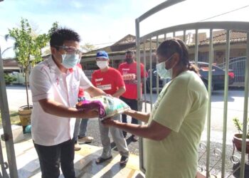 WOO Kah Leong (kiri) menyampaikan sumbangan kepada penduduk yang terjejas Covid-19 di Teluk Intan, Perak,  baru-baru ini.  