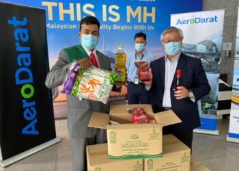 Mustapha Ahmad Marican (kiri) menunjukkan barang keperluan asas dari bakul makanan kepada Mohd. Nadziruddin di KLIA, Sepang, hari ini.