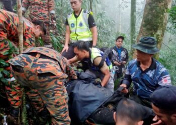 PASUKAN Bomba dan Penyelamat bersama anggota polis membantu mangsa yang cedera dalam kejadian helikopter terhempas di Brincang, Cameron Highlands, Pahang.  - MEDIA SOSIAL