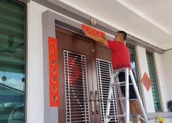 LIEW Koon Yan melekatkan tulisan kaligrafi ‘Chun Lian’ di pintu rumahnya di Bandar Utama, Gua Musang, Kelantan, hari ini. - UTUSAN/AIMUNI TUAN LAH