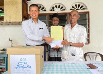 MUSTAFA Draman (kiri) menyerahkan pencen penakat dan sumbangan barangan keperluan kepada Yusof Mat di Kampung Permatang Berangan, Pulau Pinang hari ini. - Pix: SITI NUR MAS ERAH AMRAN