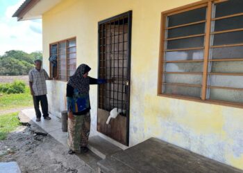 Bahari Man (kiri) dan Hamiah Osman (kanan) 
meninjau keadaan rumah adiknya yang terletak bersebelahan kediamannya di Kampung Lat 1000, Simpang Empat, Perlis semalam. - UTUSAN/ASYRAF MUHAMMAD