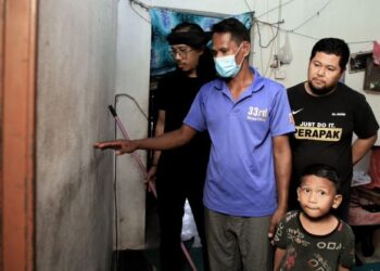 MOHAMAD Mat Yusof (dua dari kiri) menunjukkan kesan paras air di dalam rumahnya ketika banjir melanda kampung Rong Chenok, Pasir Mas, Kelantan baru-baru ini. – Mingguan/KAMARUL BISMI KAMARUZAMAN.