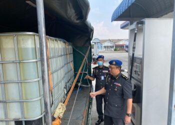 PEGAWAI penguat kuasa KPDNHEP Perak memeriksa tangki plastik berisi minyak diesel bersubsidi yang dirampas dalam serbuan di stesen minyak di Pusing, Batu Gajah, Perak, semalam. - IHSAN KPDNHEP PERAK