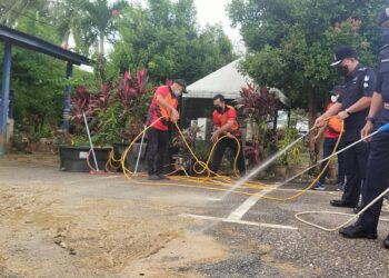 RAZARUDIN Husain (kanan) membersihkan sisa lumpur di Balai Polis Manir di Kuala Terengganu, hari ini.
