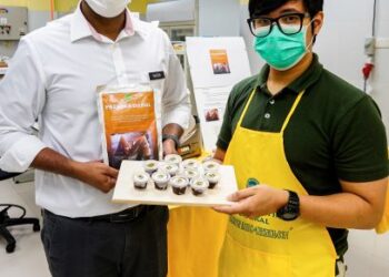 MOHAMED NAZIM ANVARALI (kiri) bersama Mohd. Faiz Che Mohd. Noor menunjukkan dodol dua minit yang siap dimasak dan disimpan di dalam bekas plastik untuk penyimpanan.