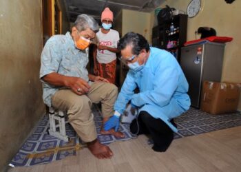 DR. Zaini Abu Bakar (kanan) memeriksa keadaan Abdul Wahab Jaafar yang mengalami sakit bengkak sendi dengan datang sendiri ke rumah pesakit di Taman Sri Pulai. Johor Bahru di Johor. - UTUSAN/RAJA JAAFAR ALI
