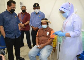 CHE Murad Sayang Ramjan (kiri) dan Ismail Ahmad (tiga dari kiri) melihat seorang tok batin yang mengambil suntikan vaksin dos pertamanya dalam Program Duta Vaksin Orang Asli Daerah Seremban di Dewan Majlis Bandaraya Seremban (MBS) di Seremban hari ini. UTUSAN/ZAKKINA WATI AHMAD TARMIZI.