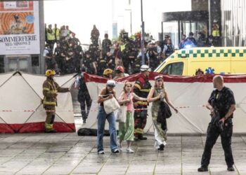 PENGUNJUNG meninggalkan pusat beli-belah Fields sambil dikawal polis selepas insiden tembakan berlaku di Copenhagen, Denmark. - AFP