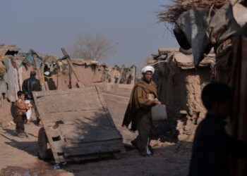 PELARIAN Afghanistan berjalan di luar rumah mereka di sebuah kem pelarian di Islamabad. - AFP