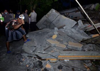 SEORANG penduduk kampung menggunakan tukul memecahkan kepingan konkrit dari sebuah rumah yang roboh akibat gempa di Malang, Indonesia. - AFP