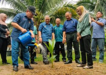 AHMAD Hamzah (depan, kiri) menyiram pokok kelapa pandan sempena Program Walkabout Kelapa di Pusat Pertanian Padang Matsirat di Langkawi, hari ini. -UTUSAN/NUR AMALINA AZMAN