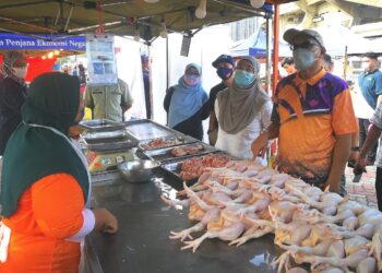IZHAM Hashim (kanan) bertanya khabar kepada seorang penjual ayam segar di Pasar Tani Stadium Shah Alam, Selangor, hari ini. - UTUSAN / ABDUL RAZAK IDRIS
