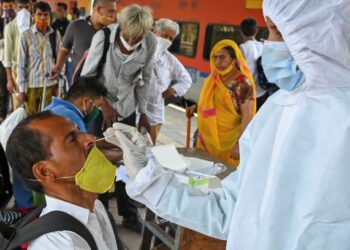PETUGAS kesihatan mengambil sampel calitan di hidung terhadap seorang penumpang kereta api di Mumbai. -AFP