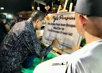 TAKIYUDDIN Hassan (kiri) menandatangani plak dan gimik pelancaran Pintu Gerbang Pasar Malam Wakaf Che Yeh, Kelantan. - UTUSAN/ROSLIZA MOHAMED
