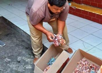 SAMIN menunjukkan wang yang sudah rosak akibat dimakan anai-anai.TRIBUN