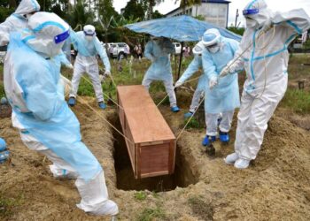 PETUGAS yang mengenakan pakaian perlindungan diri (PPE) mengebumikan individu yang dijangkiti Covid-19 di wilayah Narathiwat, Thailand. - AFP
