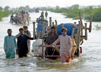 PENDUDUK membawa barangan mengharungi jalan dinaiki air selepas banjir melanda Sohbatpur di Jaffarabad di wilayah Balochistan. - AFP