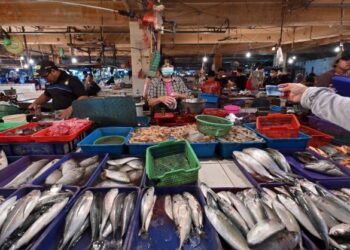 PENIAGA menjual ikan kepada pelanggan di pasar di Tangerang, Jakarta. - AFP
