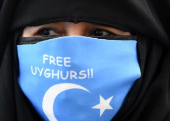 SEORANG wanita Uighur memakai pelitup muka tertera bendera timur Turkestan semasa demonstrasi di depan bangunan Konsulat China di Istanbul, tahun lalu.-AFP
