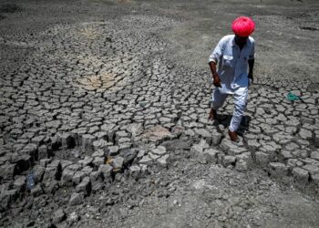 PENDUDUK berjalan di atas di kolam yang kering akibat gelombang haba di kampung Bandai, wilayah Pali, Rajasthan. - AFP