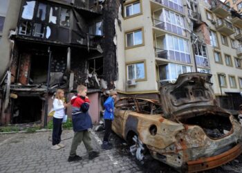 KANAK-KANAK melihat bangkai kereta yang terbakar akibat serangan udara di Kramatorsk, Ukraine. - AFP