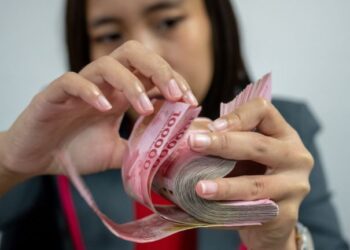 PENGURUP mata wang berlesen mengira kepingan wang kertas rupiah sebelum diberikan kepada pelanggan di Jakarta.-AFP