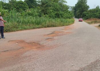 SEORANG penduduk menunjukkan jalan berlopak antara Jalan Sungai Pasir ke Padang Tembusu di Sungai Petani, Kedah.  – IHSAN PEMBACA