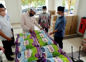 IDRIS Ahmad melihat beras yang disumbangkan badan korporat untuk diserahkan kepada kariah terjejas di sekitar Putrajaya. - UTUSAN/MOHD. HUSNI MOHD. NOOR