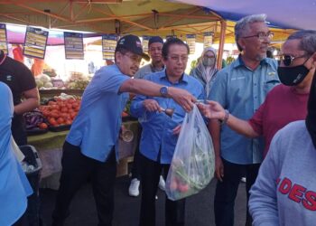 ABDUL Rashid Bahri (kiri) mengedarkan Combo Madani kepada orang ramai di Pasar Tani Putrajaya. - UTUSAN/MOHD HUSNI MOHD NOOR
