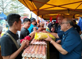 MOHD. Zolkafly Harun (kanan) menjual telur ayam kepada pengunjung sempena 'happy hour' pada program Jualan Ramadan Madani di Pasar Tani Tapah, Tapah hari ini. - UTUSAN