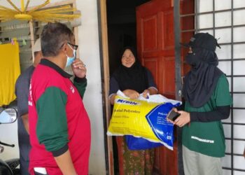 NORFARAHIN Romli (kanan) dan Hanafiah Mat (dua dari kiri) menyerahkan kit solat dan barangan keperluan untuk mangsa banjir di Taman Fikri, Kemaman hari ini.