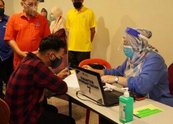 ABDUL Fattah Abdullah (baju merah) melihat petugas PPUM mengendalikan proses pemberian vaksin ketika memberi sumbangan kepada petugas barisan hadapan di PPUM, Petaling Jaya hari ini.
