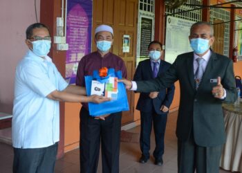 TUN Ahmad Faisal Tun Abdul Razak (kanan) menerima sumbangan telefon pintar daripada penyumbang Program Cakna Didik Marang Hebak di pekarangan Pejabat Pendidikan Daerah Marang, Terengganu, hari ini. - UTUSAN/PUQTRA HAIRRY ROSLI